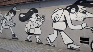 Graffiti auf der Mauer in einer Stadt in Frankreich - es sind Menschen in ihrem Alltag dargestellt, wie sie mit dem Handy laufen, Kinderwagen schieben