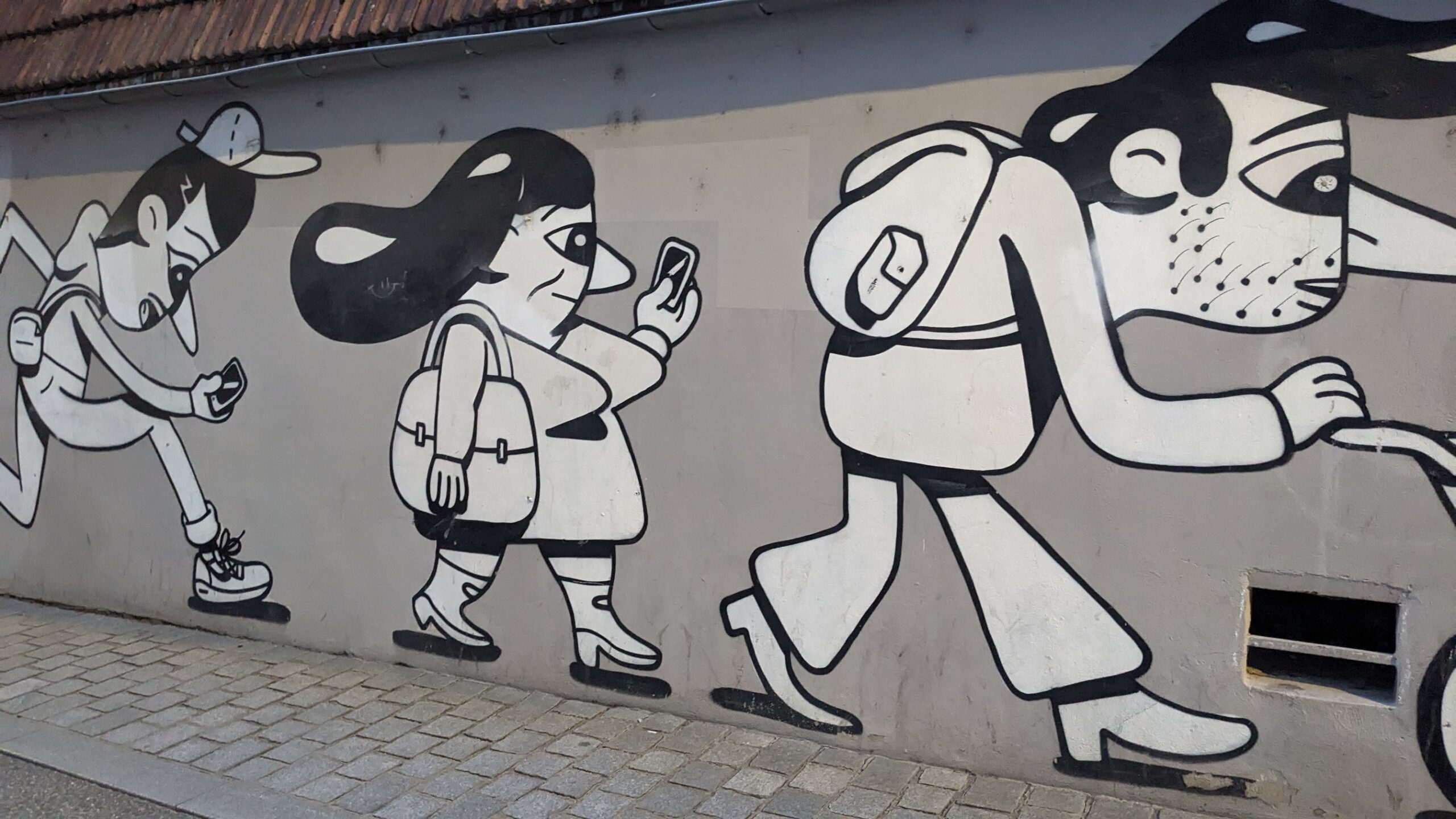 Graffiti auf der Mauer in einer Stadt in Frankreich - es sind Menschen in ihrem Alltag dargestellt, wie sie mit dem Handy laufen, Kinderwagen schieben