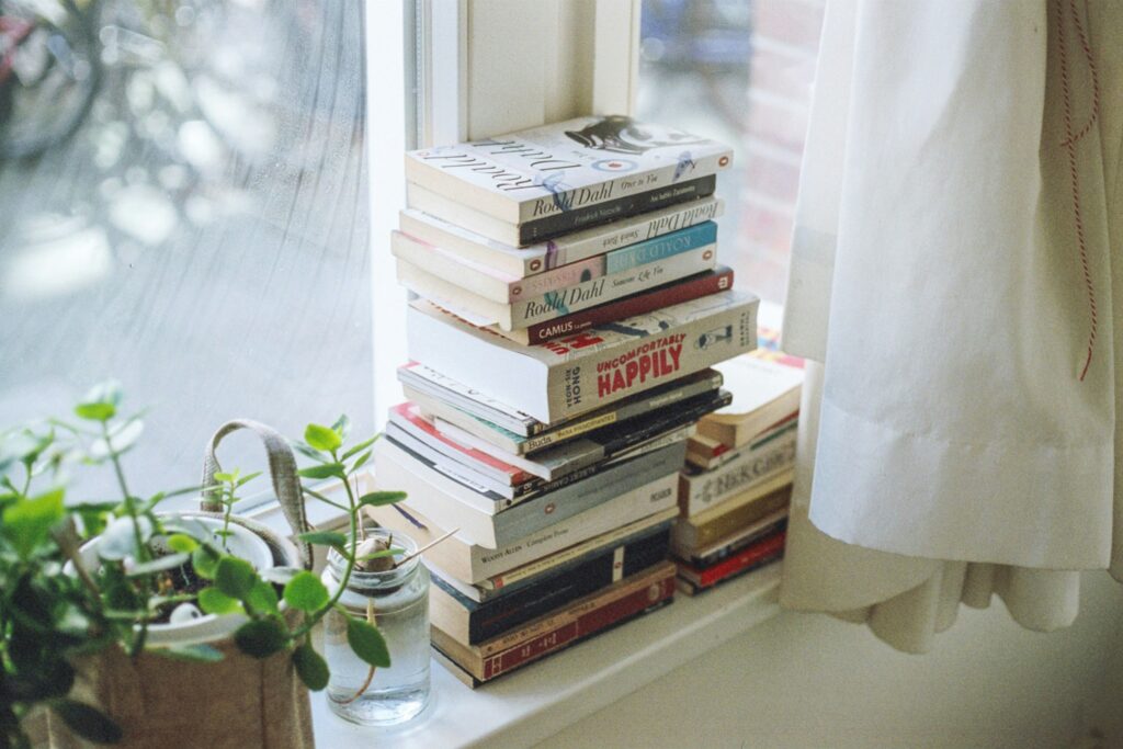 Cozy winter scene with books and soft light, representing rest, reflection, and the healing power of reading; photo by Florencia Viadana on Unsplash.