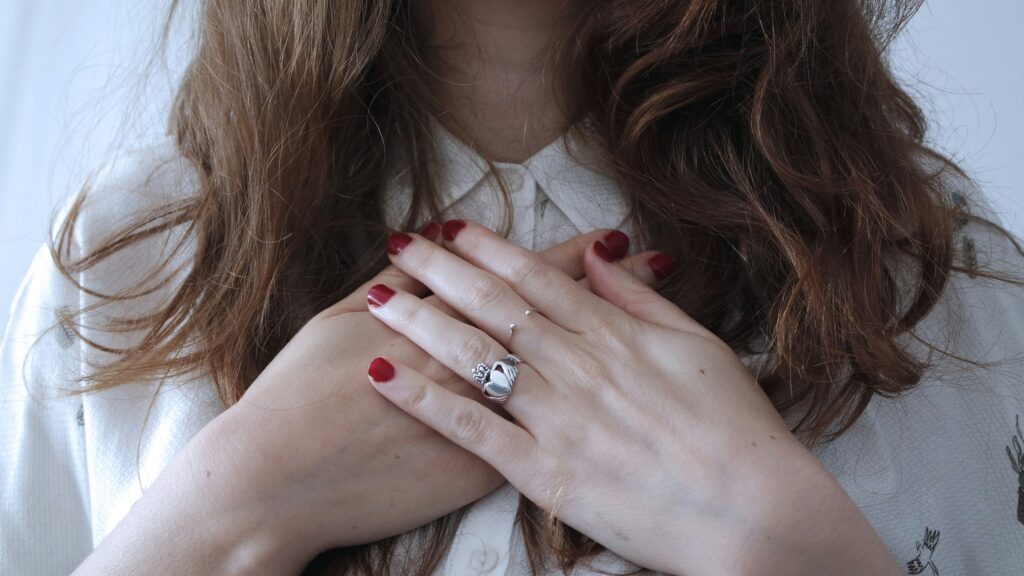 Frau trägt silberfarbenen Ring und hält ihre Hände auf dem Herz, Bild von Giulia Bertelli